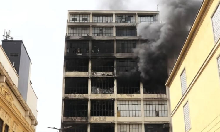 Incêndio em edifício comercial com fumaça preta, destacando a importância do alvará do Corpo de Bomb.