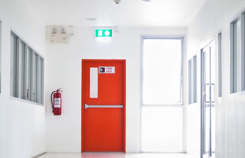 Porta corta fogo vermelha instalada em corredor de segurança.