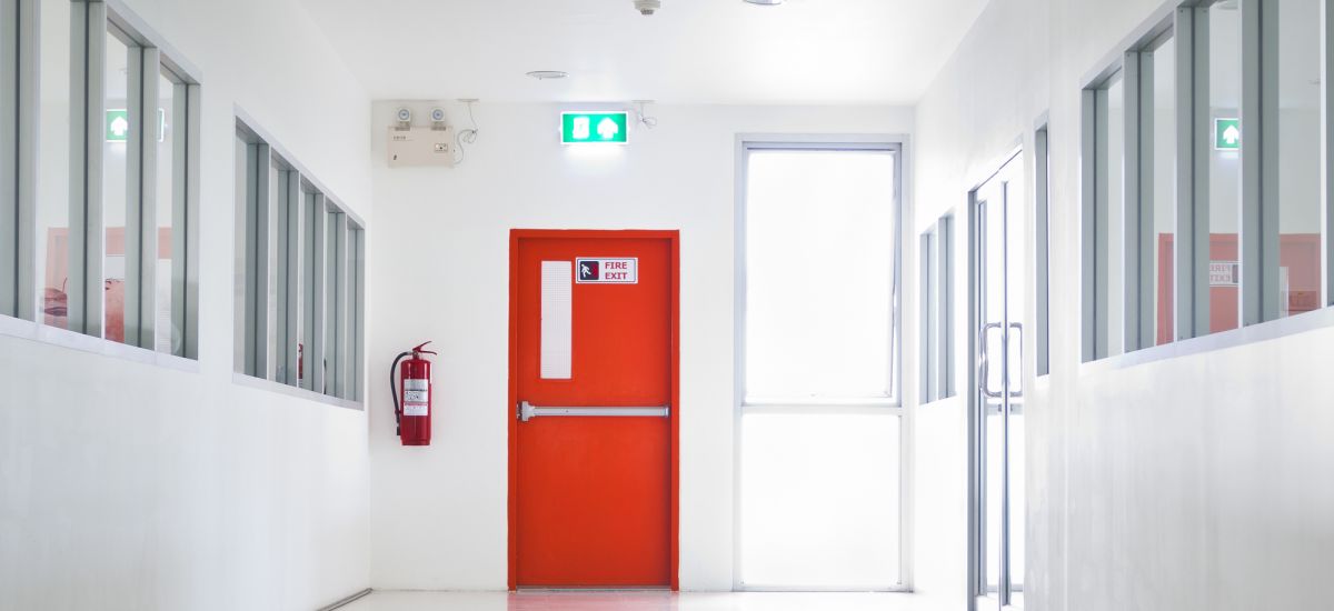 Porta corta fogo vermelha instalada em corredor de segurança.