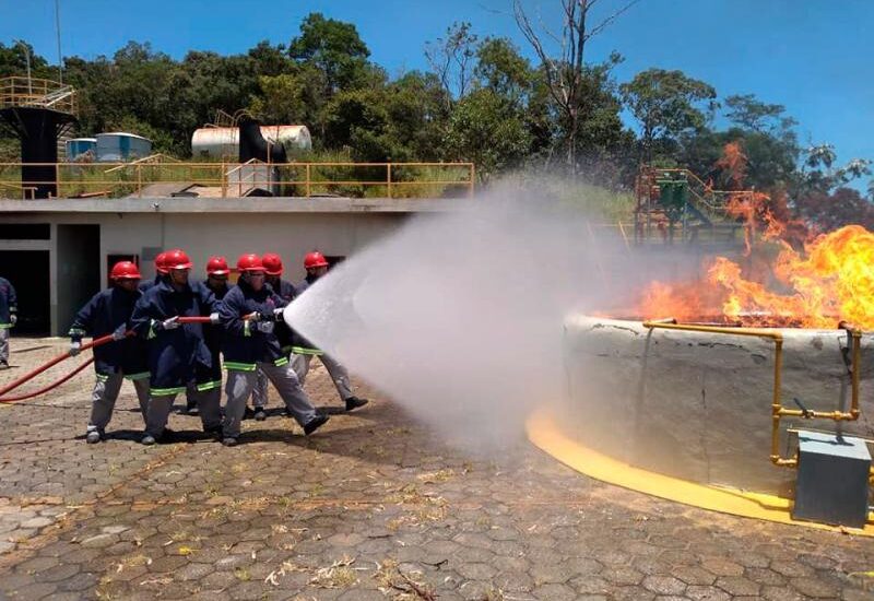 Equipe treinada combate incêndio com mangueira de alta pressão.