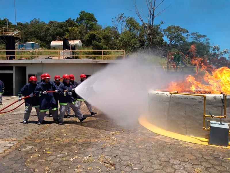 Equipe treinada combate incêndio com mangueira de alta pressão.