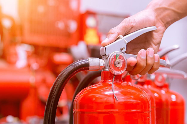 Pessoa manuseando extintor de incêndio em ambiente de segurança.