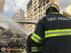 Bombeiro de São Paulo combate incêndio em prédio com mangueira de água.
