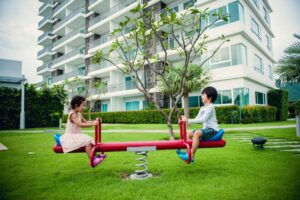 Balanço de parque com duas crianças brincando ao ar livre.