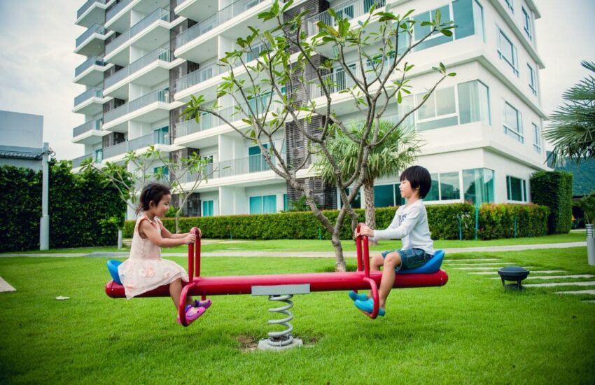 Balanço de parque com duas crianças brincando ao ar livre.